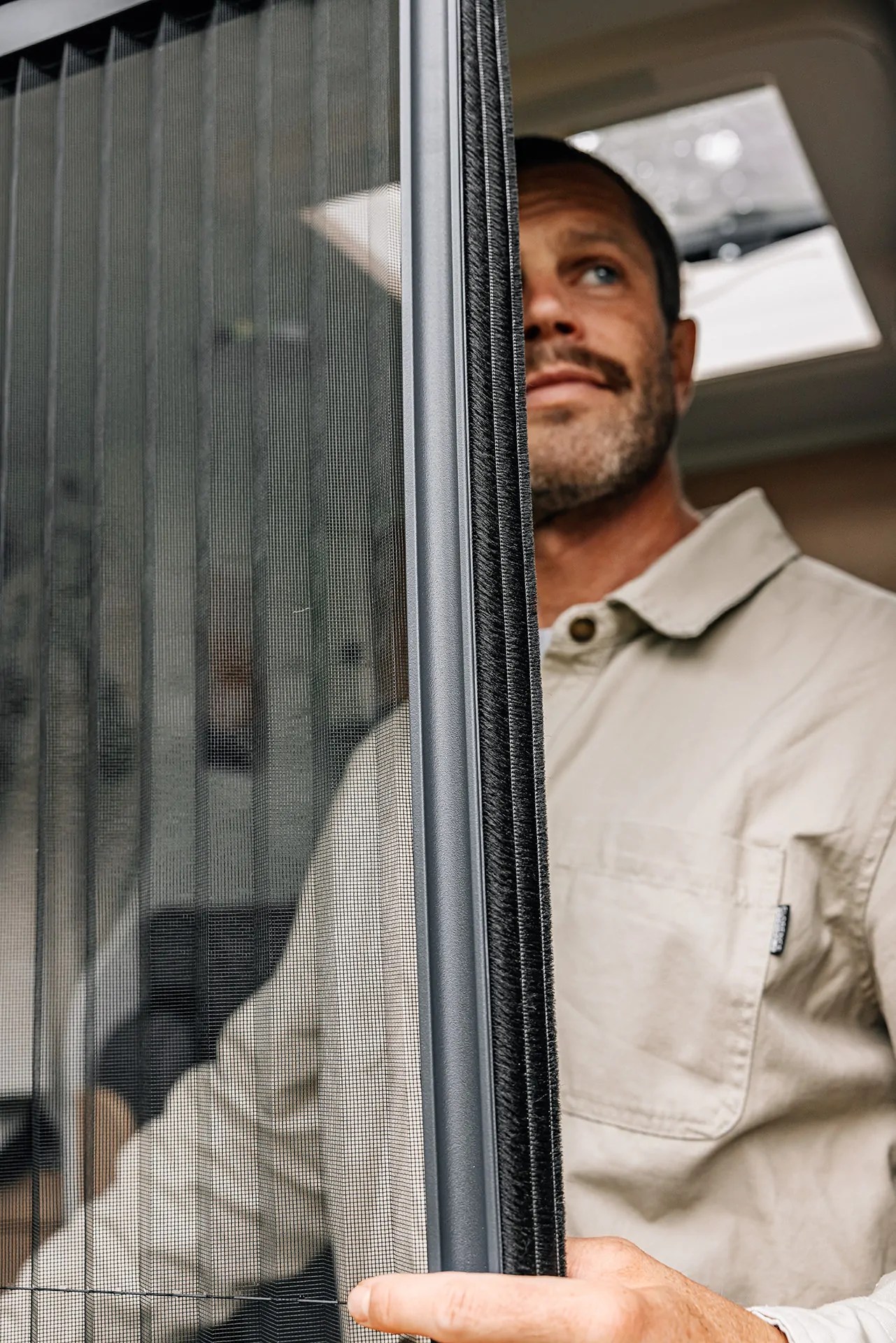 Ein Mann öffnet eine Fliegengittertür in einem Sunlight Cliff Camper.
