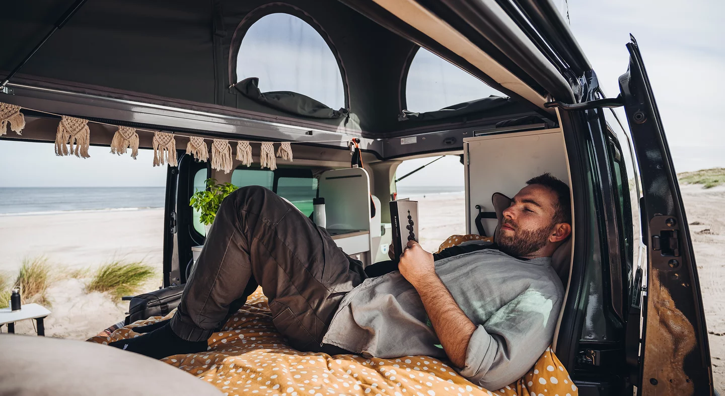 Ein Mann entspannt sich in einem Camper am Strand.
