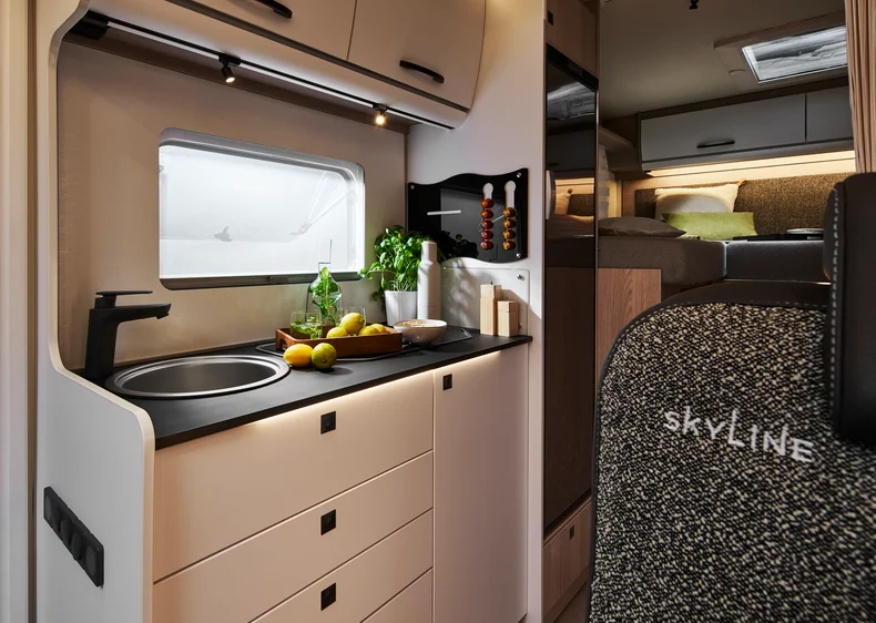 Kompakte Küche im Bürstner Lyseo Time Skyline Wohnmobil mit Spüle, Kochutensilien und Kräutern.