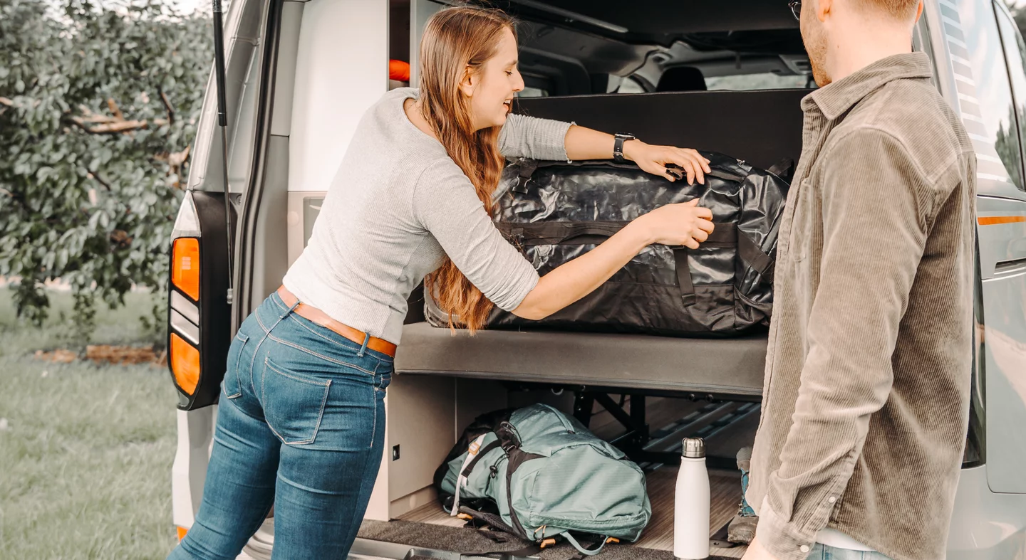 Eine Frau verstaut Gepäck im Kofferraum eines Ford Campers.