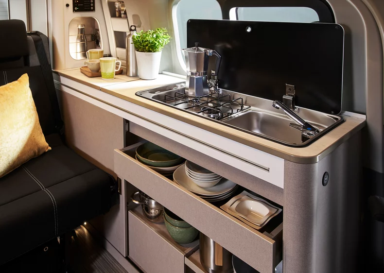 Innenraum eines Copa mit Küchenzeile, Gasherd und Spüle.