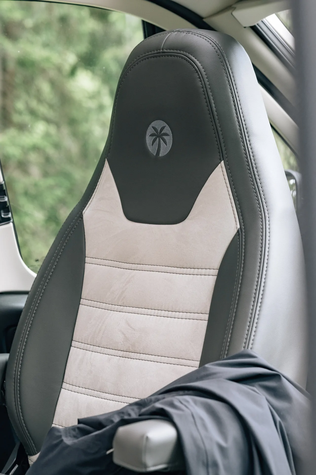 Fahrzeugsitz mit zweifarbigem Design und Palmenlogo auf der Kopfstütze.