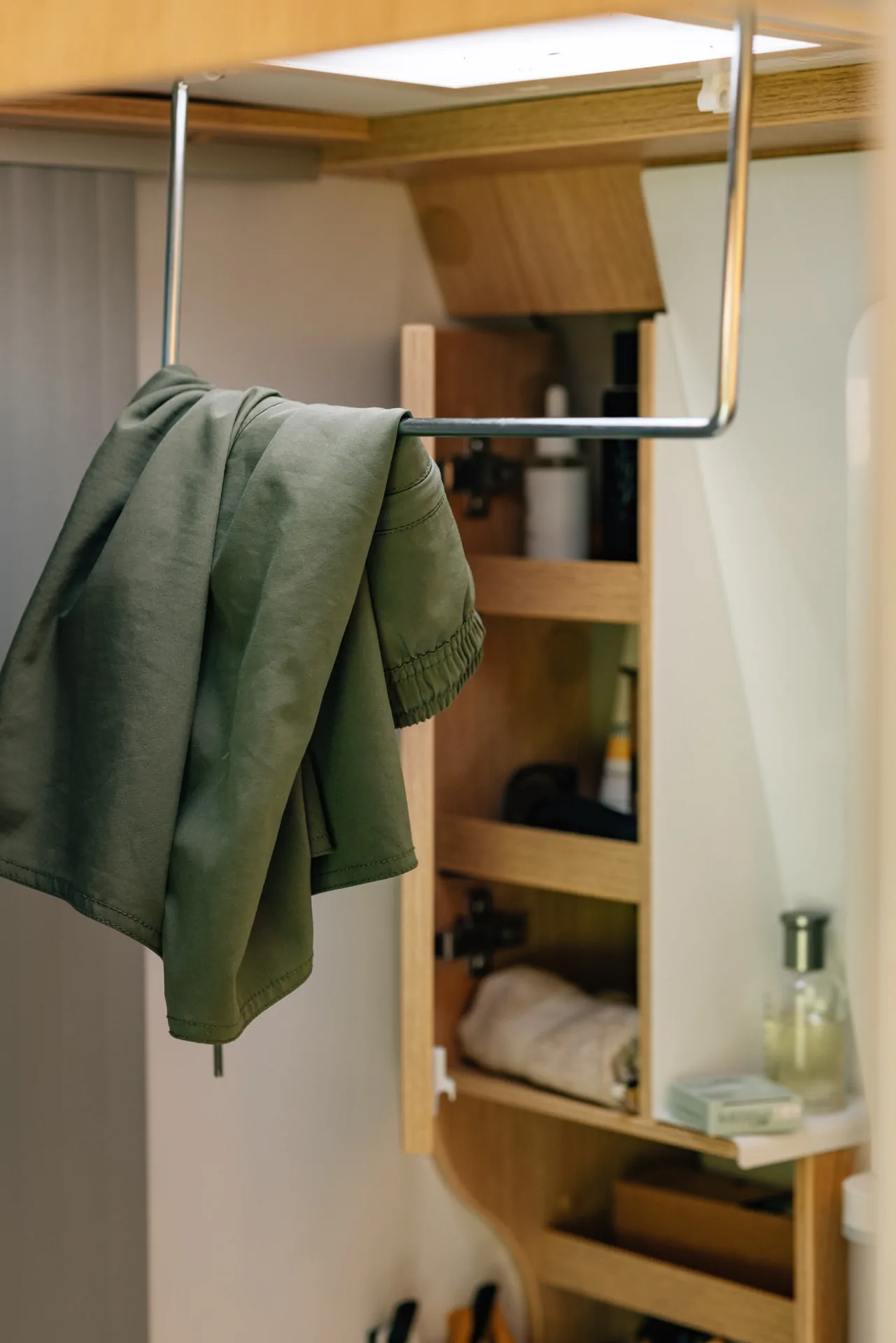 Grüne Jacke hängt auf einer Kleiderstange in einem Camper.