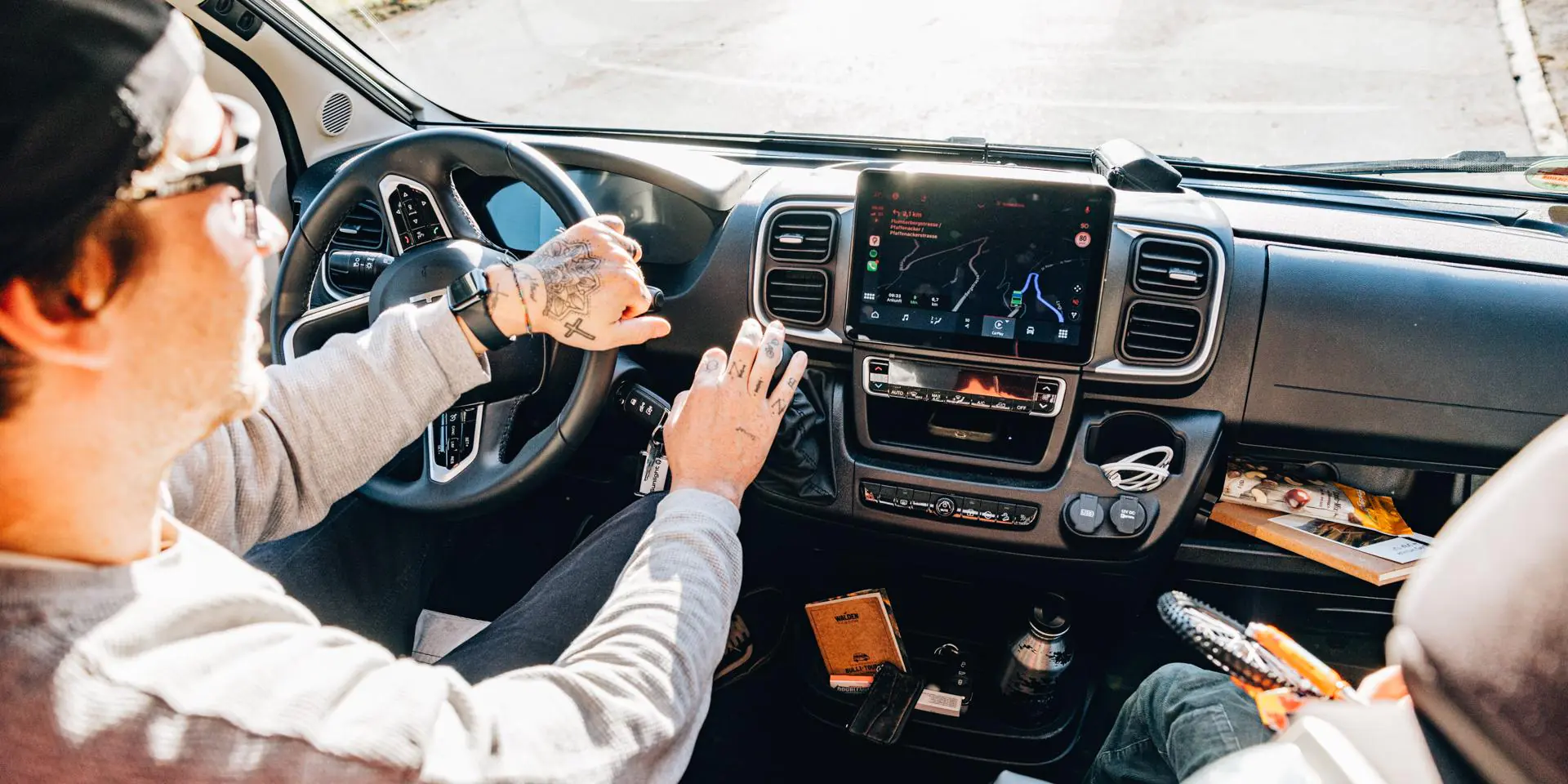 Ein Mann sitzt am Steuer eines Fahrzeugs und bedient das Navigationssystem.