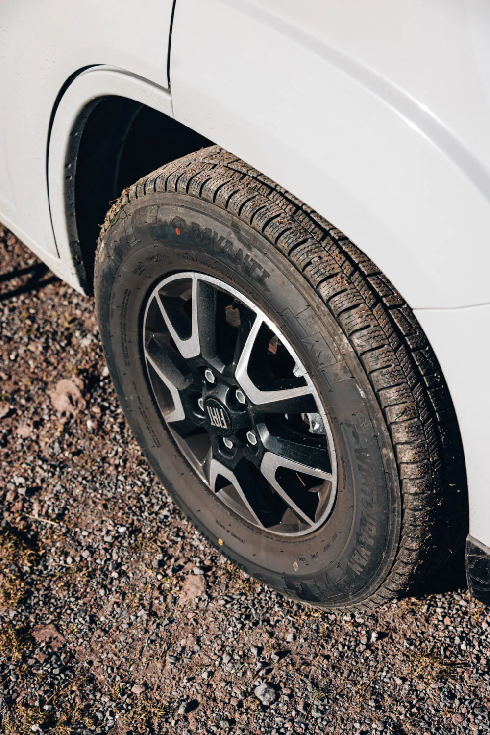 Nahaufnahme eines Autoreifens eines Cliff Adventure auf steinigem Untergrund.