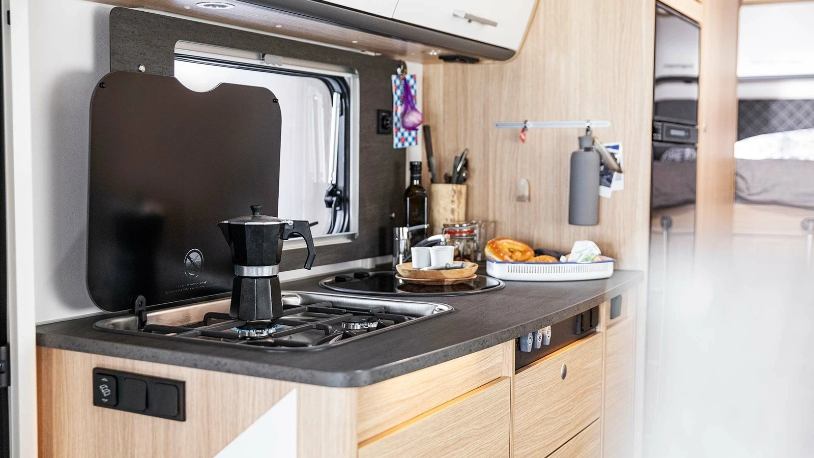 Küchenzeile in einem Wohnmobil mit Kaffeemaschine und Frühstücksutensilien.