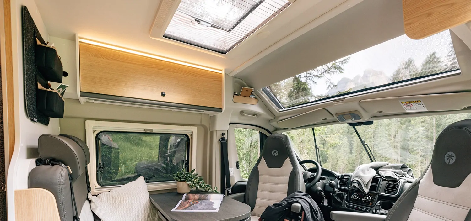 Innenansicht eines Sunlight Cliff X Wohnmobils mit Tisch, Pflanzen und Sitzen.