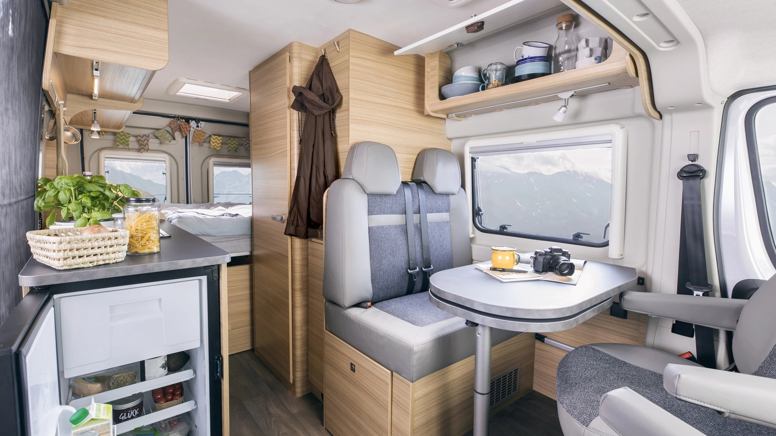 Innenansicht eines Sunlight Cliff Camper Vans mit Sitzbereich, Tisch und Küchenzeile.