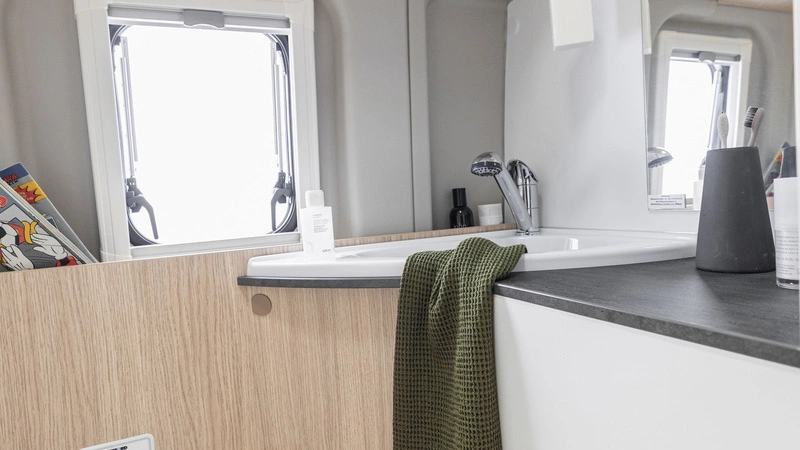 Ein modernes Wohnmobil-Badezimmer mit Waschbecken, Spiegel und Handtuch.