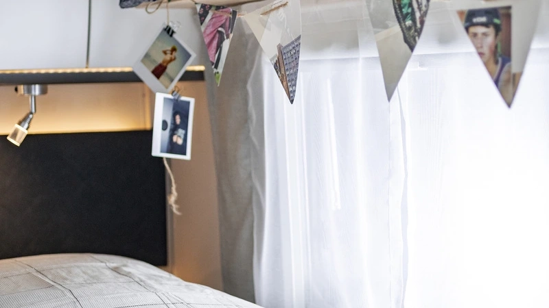 Ein gemütliches Schlafzimmer im Sunlight T67S Wohnmobil mit Fotos und Lichterkette.