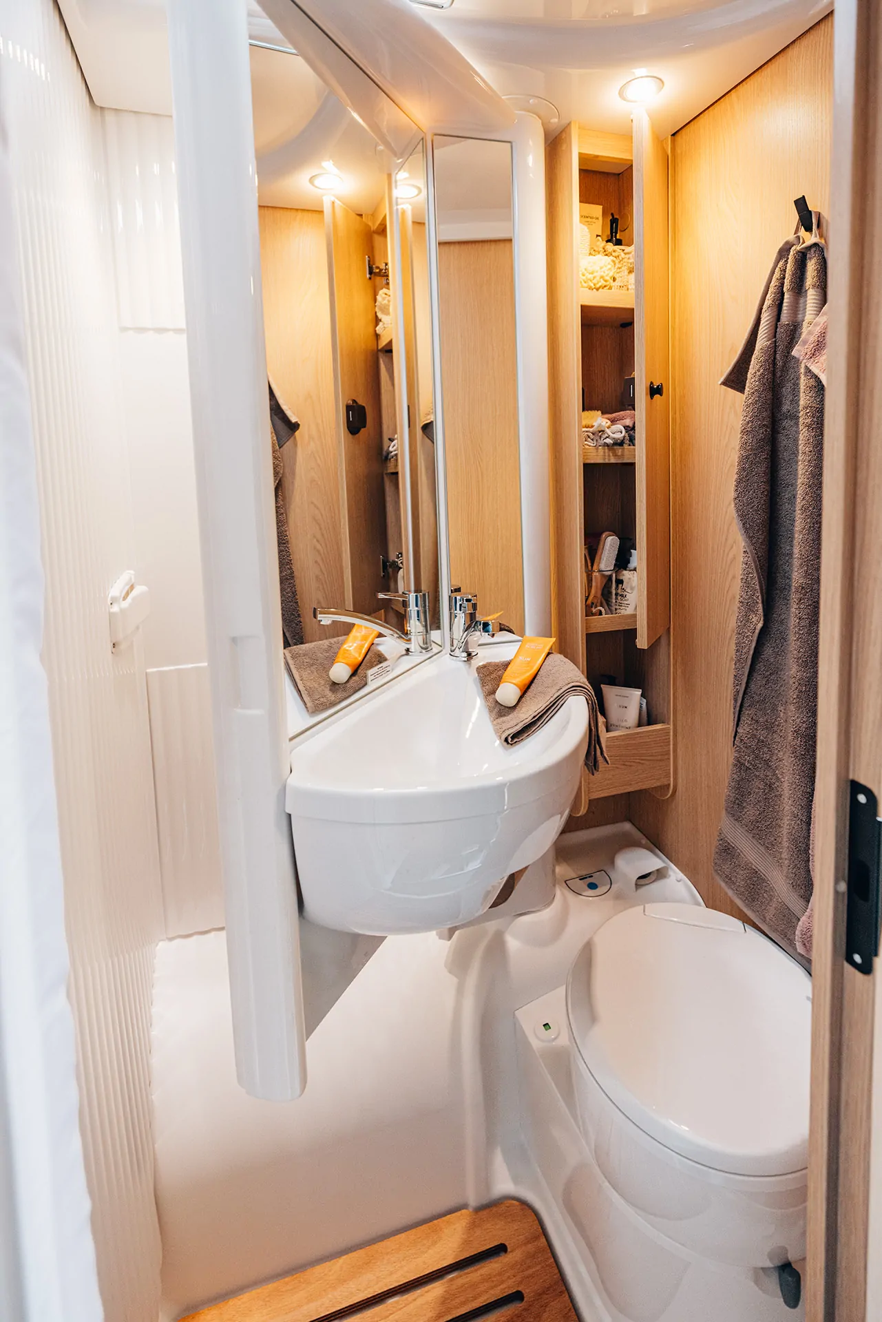 Innenansicht eines Wohnmobil-Badezimmers mit Waschbecken, Spiegel und Toilette.