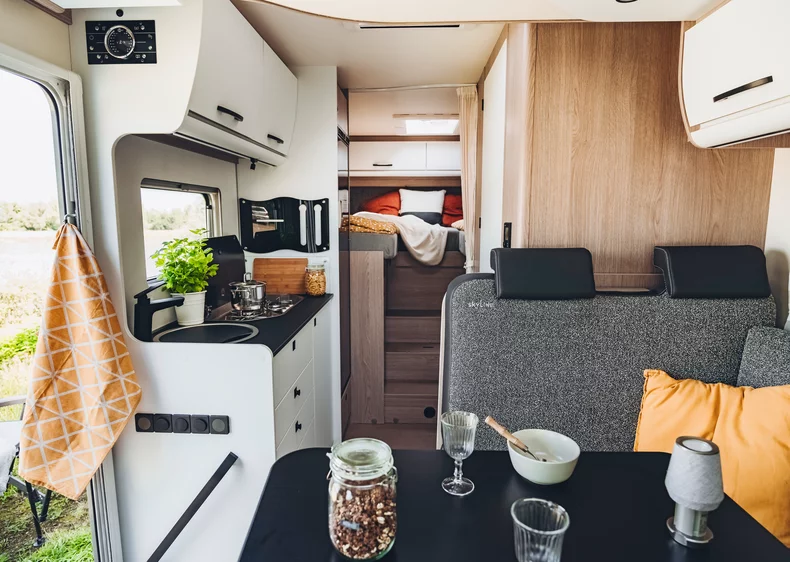 Innenansicht eines Bürstner Lyseo Time Skyline Wohnmobils mit Küche, Esstisch und Schlafbereich.