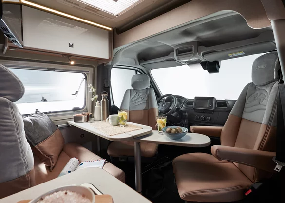 Innenraum eines Bürstner Delfin C 621 Wohnmobils mit Tisch, Sitzplätzen und Cockpit.