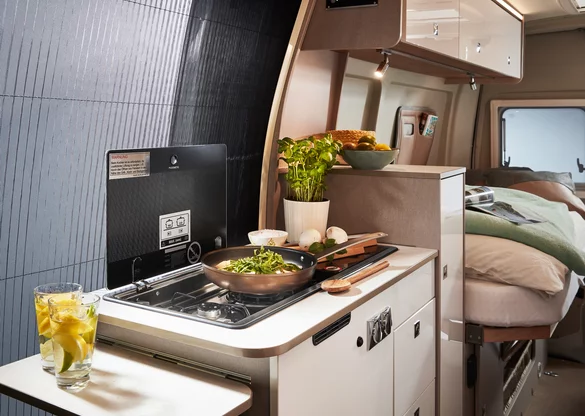 Innenraum eines Bürstner Delfin C 621 Wohnmobils mit Küchenzeile und Bett.