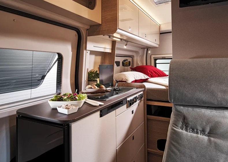 Innenraum eines Bürstner Lineo 4x4 C590 Wohnmobils mit Küche und Schlafbereich.