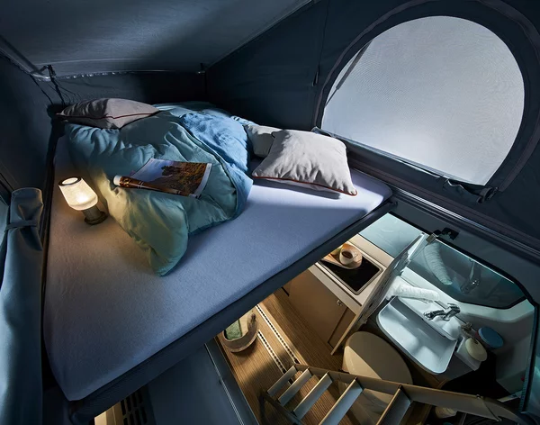Innenraum eines Bürstner Wohnmobils mit einem gemütlichen Schlafbereich und einer kleinen Treppe zur Küche und Bad.