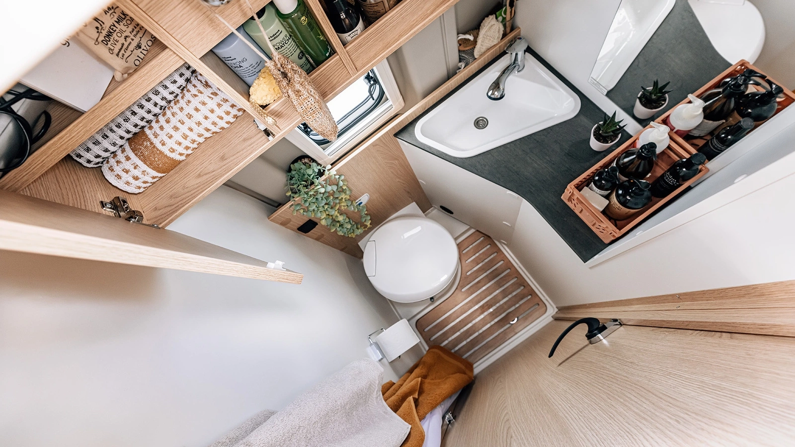 Kompaktes Badezimmer in einem Peugeot Cliff 600 Camper mit Waschbecken, Toilette und Regalen.