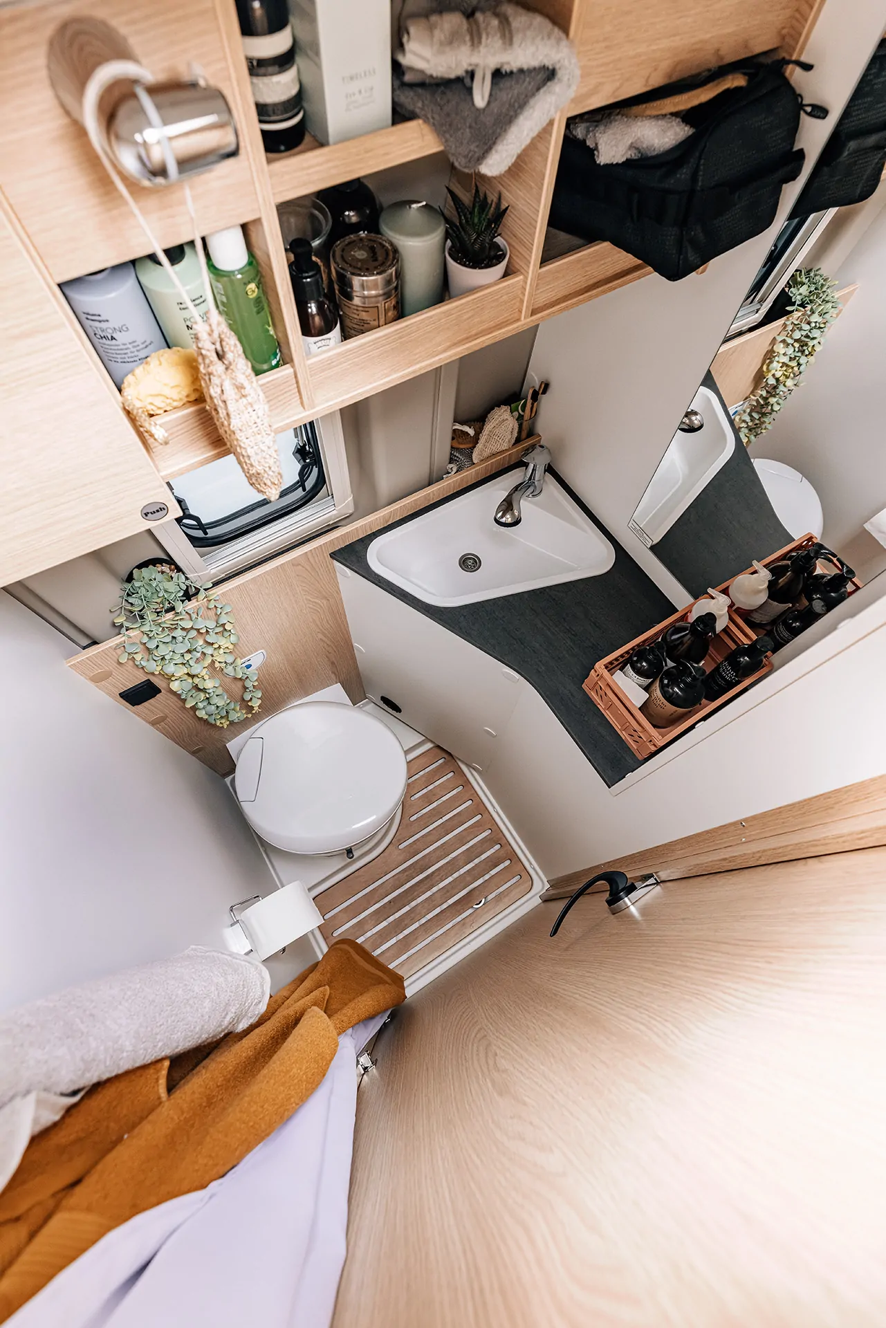 Kompaktes Badezimmer in einem Peugeot-Camper mit Waschbecken, Toilette und Regalen.