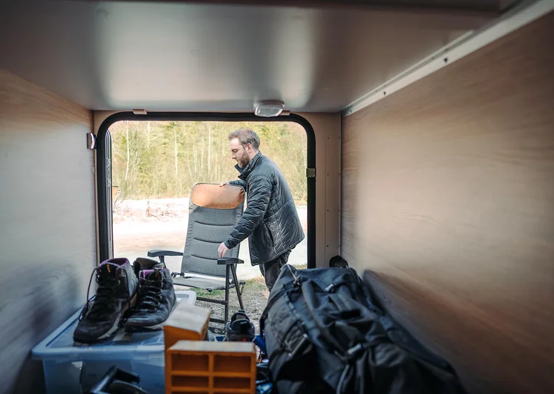 Ein Mann verstaut einen Stuhl im hinteren Teil eines Campers.