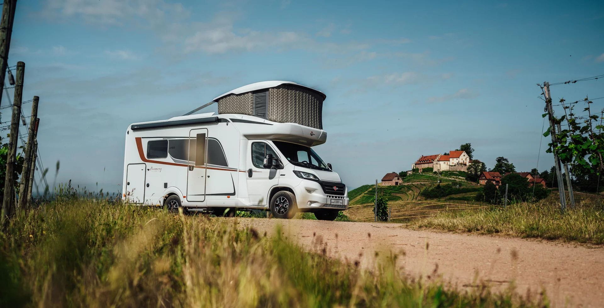 Ein Bürstner Lyseo Gallery TD Wohnmobil mit ausgefahrenem Dach steht auf einem Feldweg