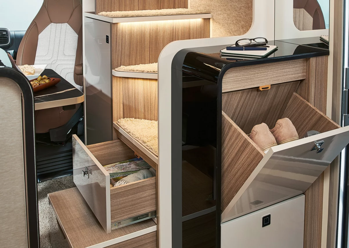 Innenraum eines Wohnmobils mit Holzstufen, Schubladen und einem Sitzbereich.