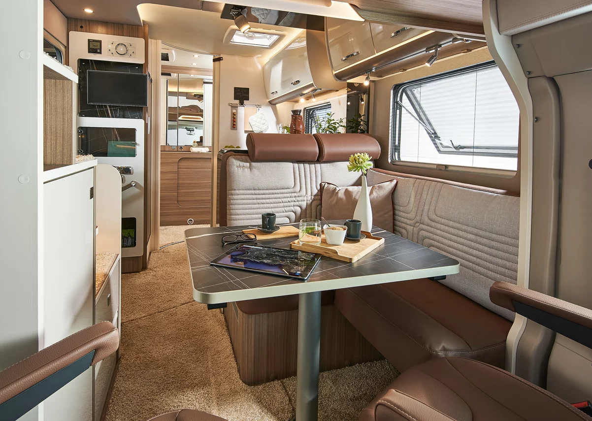 Innenansicht eines Bürstner Lyseo Wohnmobils mit Tisch, Sitzbank und Dekoration.