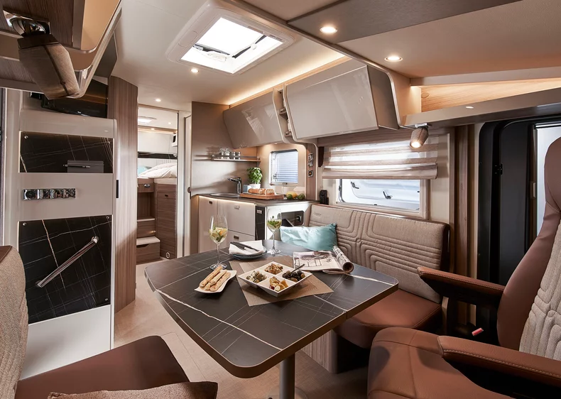 Innenansicht eines modernen Wohnmobils mit Essbereich und Küche.