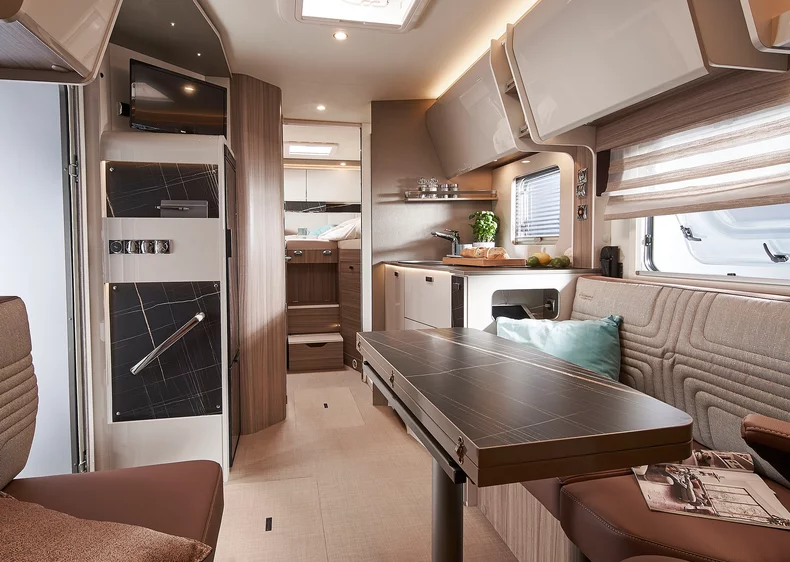 Innenraum eines modernen Bürstner Lyseo I Wohnmobils mit Essbereich, Küche und Schlafbereich im Hintergrund.