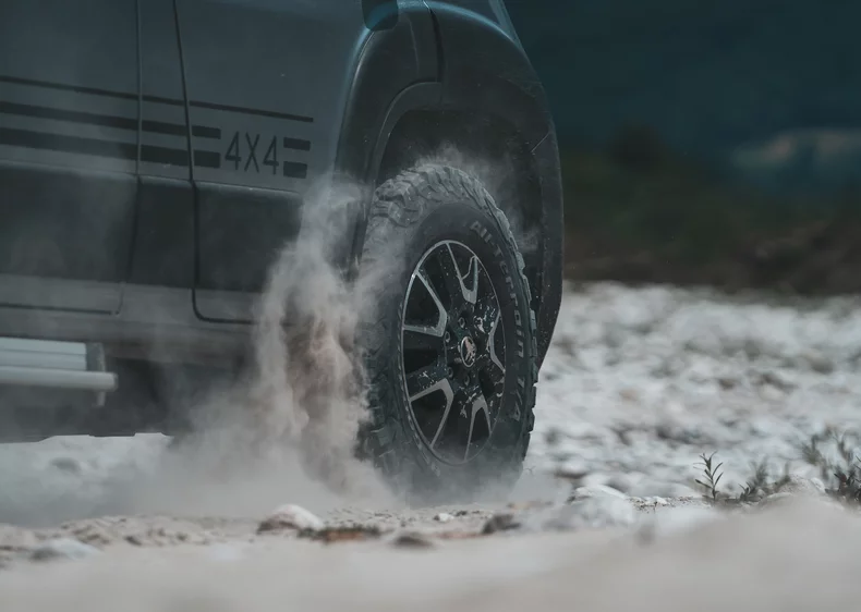 Nahaufnahme eines 4x4-Geländewagens, der durch staubiges Gelände fährt.