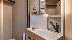 Modernes Badezimmer in einem Campeo TD 690 Wohnmobil mit Waschbecken, Spiegel und Stauraum.