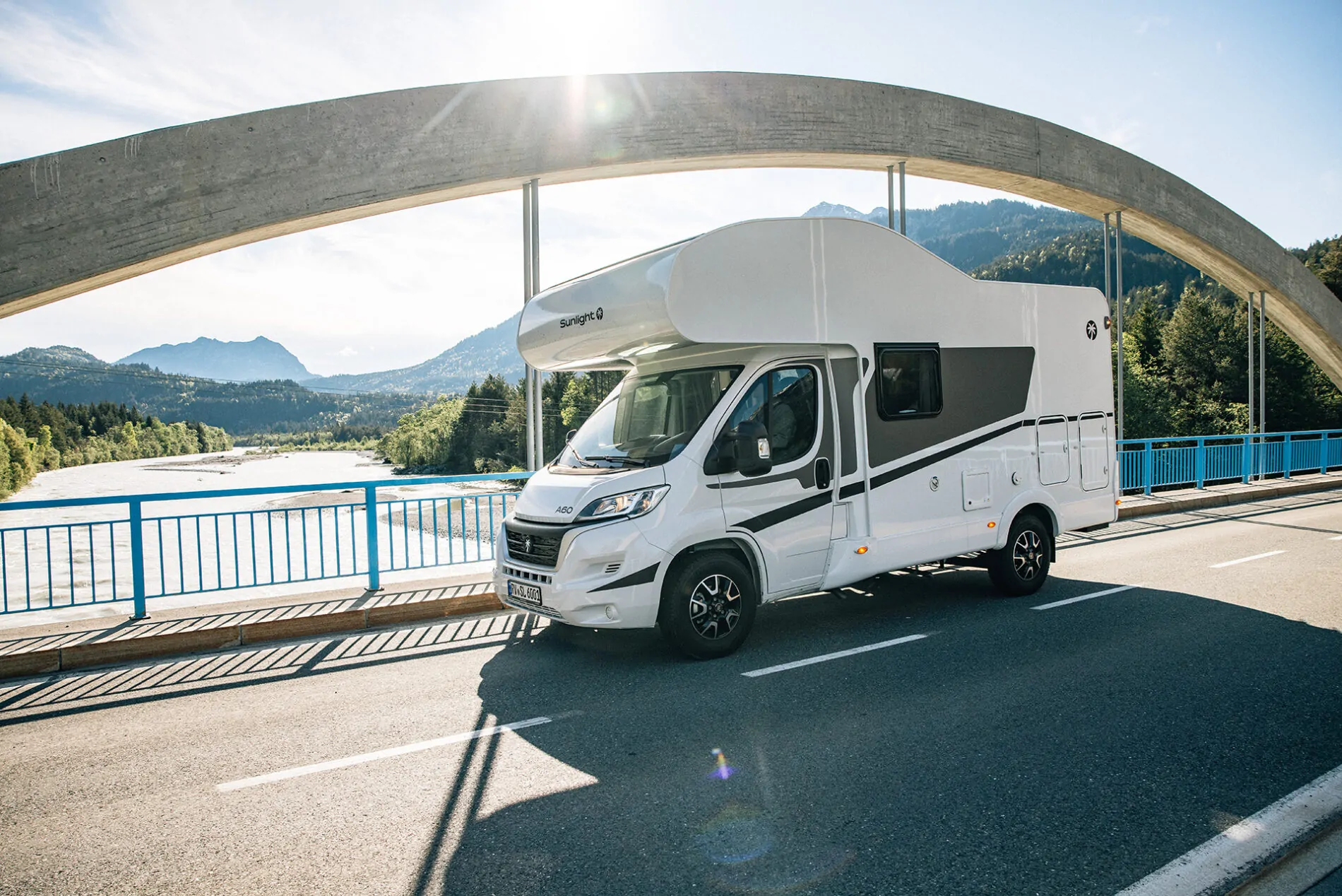 Hinterrad eines weißen Fiat-Alkoven-Wohnmobils auf einem Schotterweg.