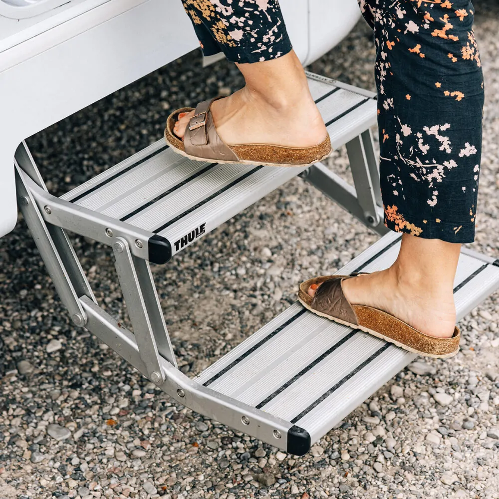 Person steigt auf eine Thule-Trittstufe eines Wohnmobils.