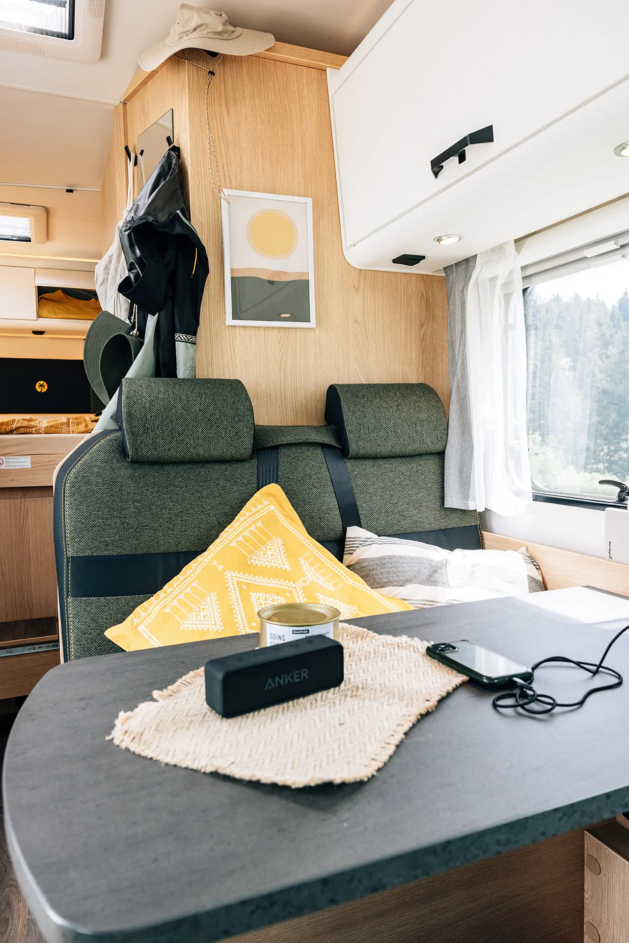 Innenansicht eines Alkoven-Wohnmobils mit Tisch, Sitzbank und Dekoration.