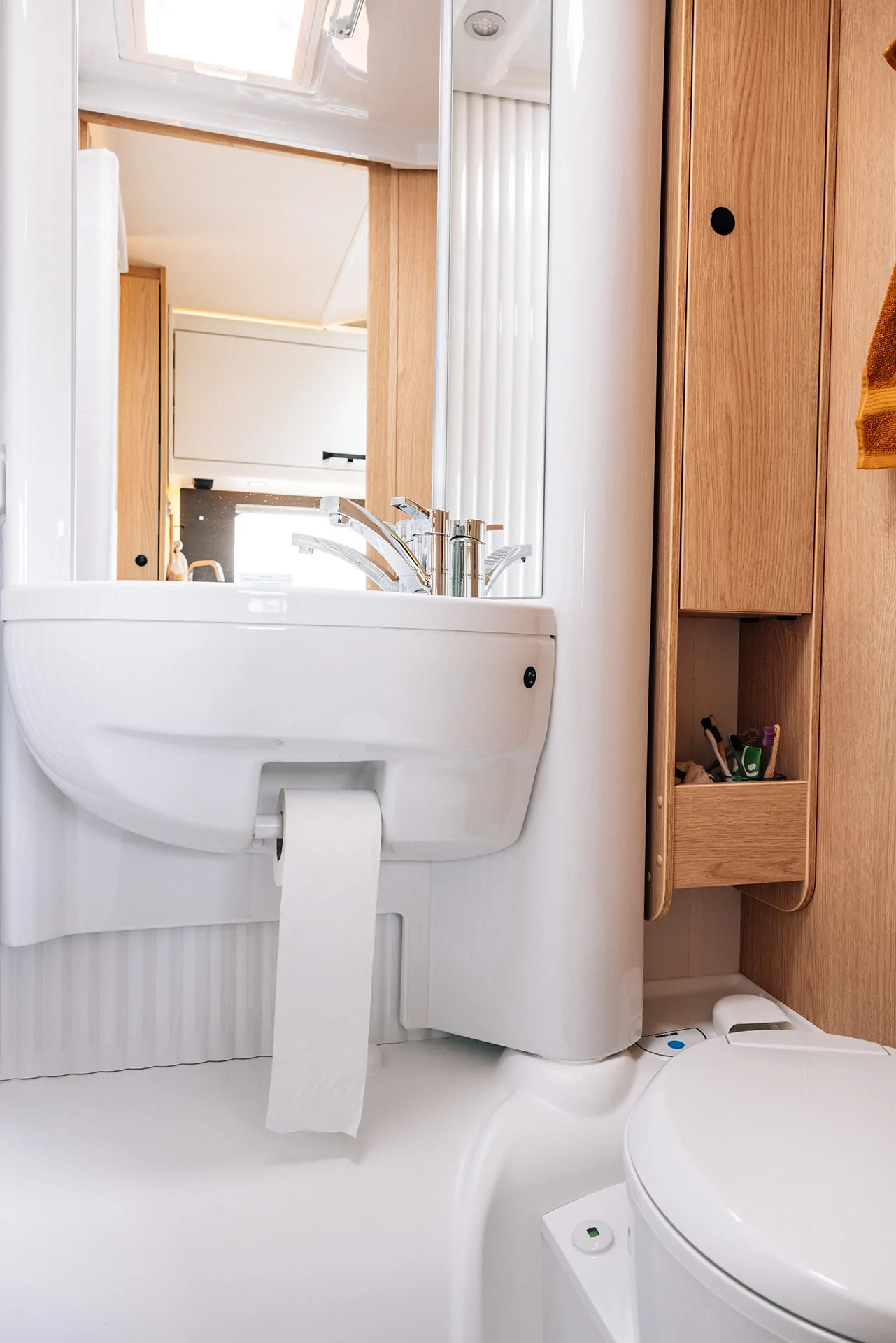 Interieur eines Wohnmobils mit Waschbecken, Toilette und Holzverkleidung.