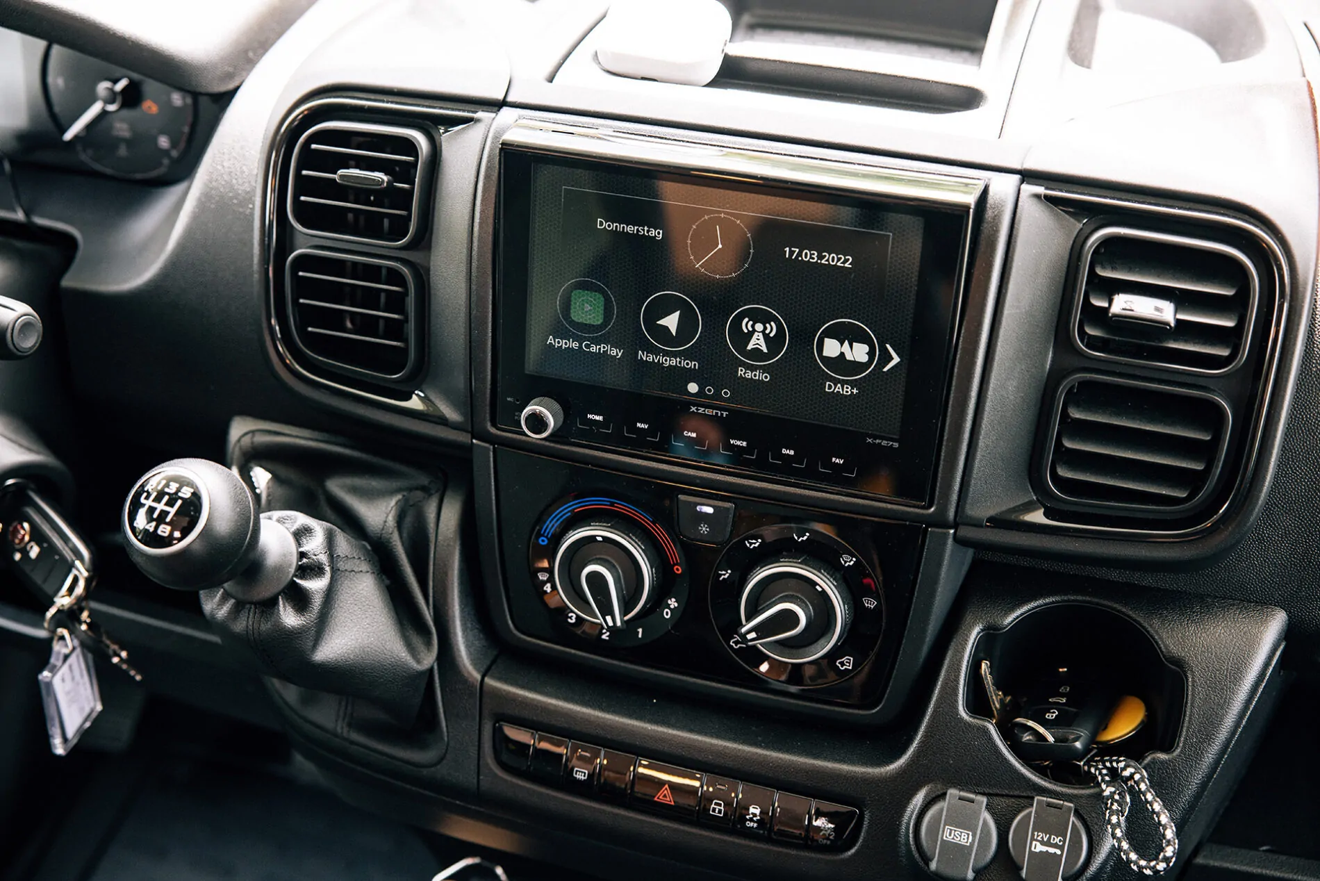 Innenraum eines Fahrzeugs mit einem Infotainmentsystem und Schalthebel.