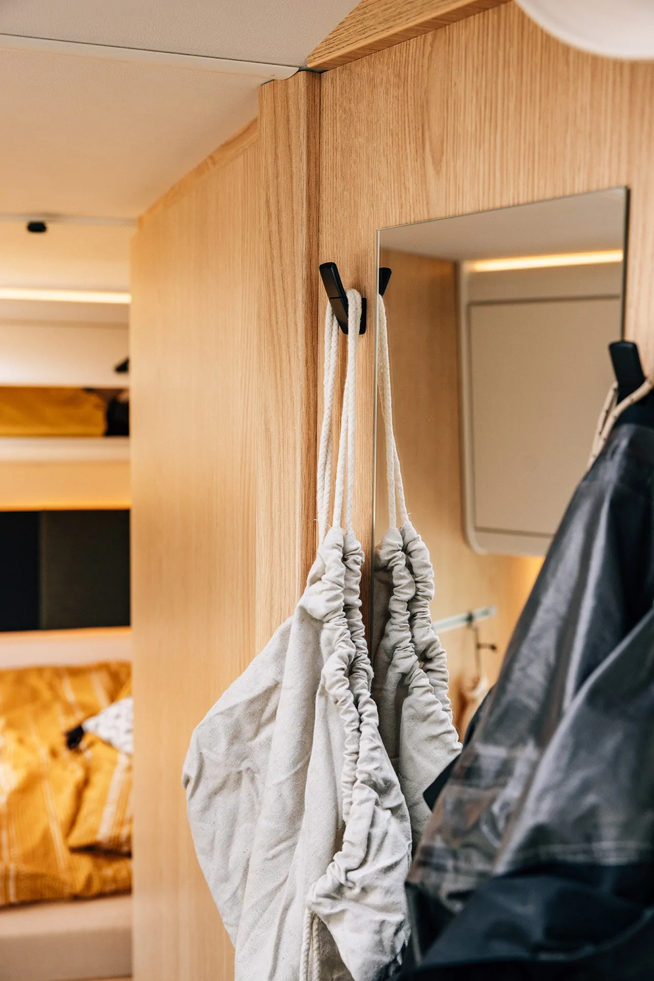 Innenraum eines Campers mit Holzwand und aufgehängten Taschen.