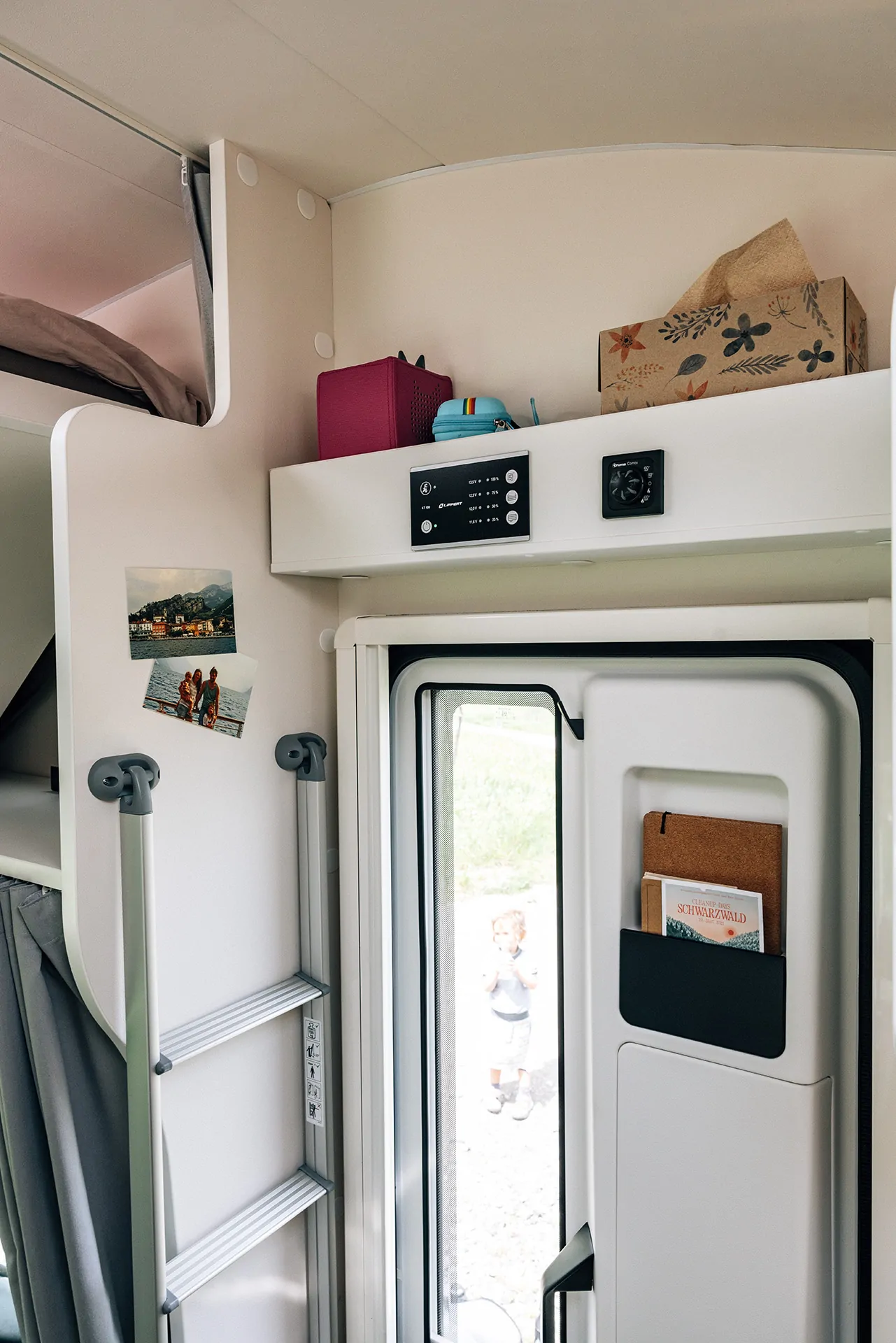 Innenansicht eines Wohnmobils mit Leiter und Dekorationen an der Wand.