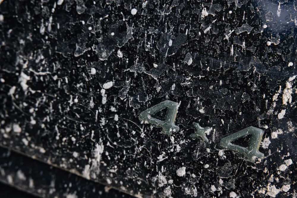 Nahaufnahme eines schmutzigen 4x4-Emblems auf einem Fahrzeug.