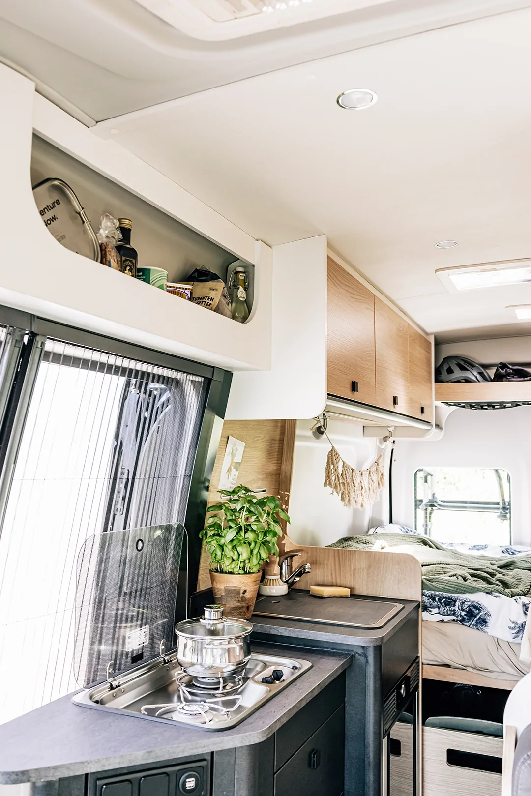Innenansicht eines Wohnmobils mit Küche, Pflanze und Bett.