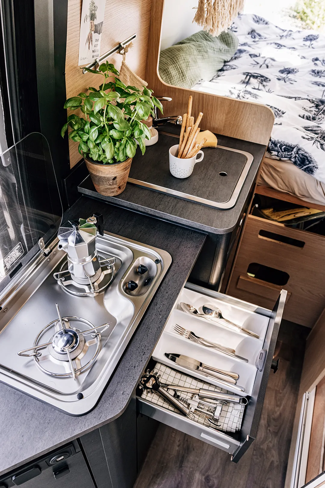 Innenansicht eines Cliff 4x4 Campers mit Küche, Basilikumtopf und Besteckschublade.