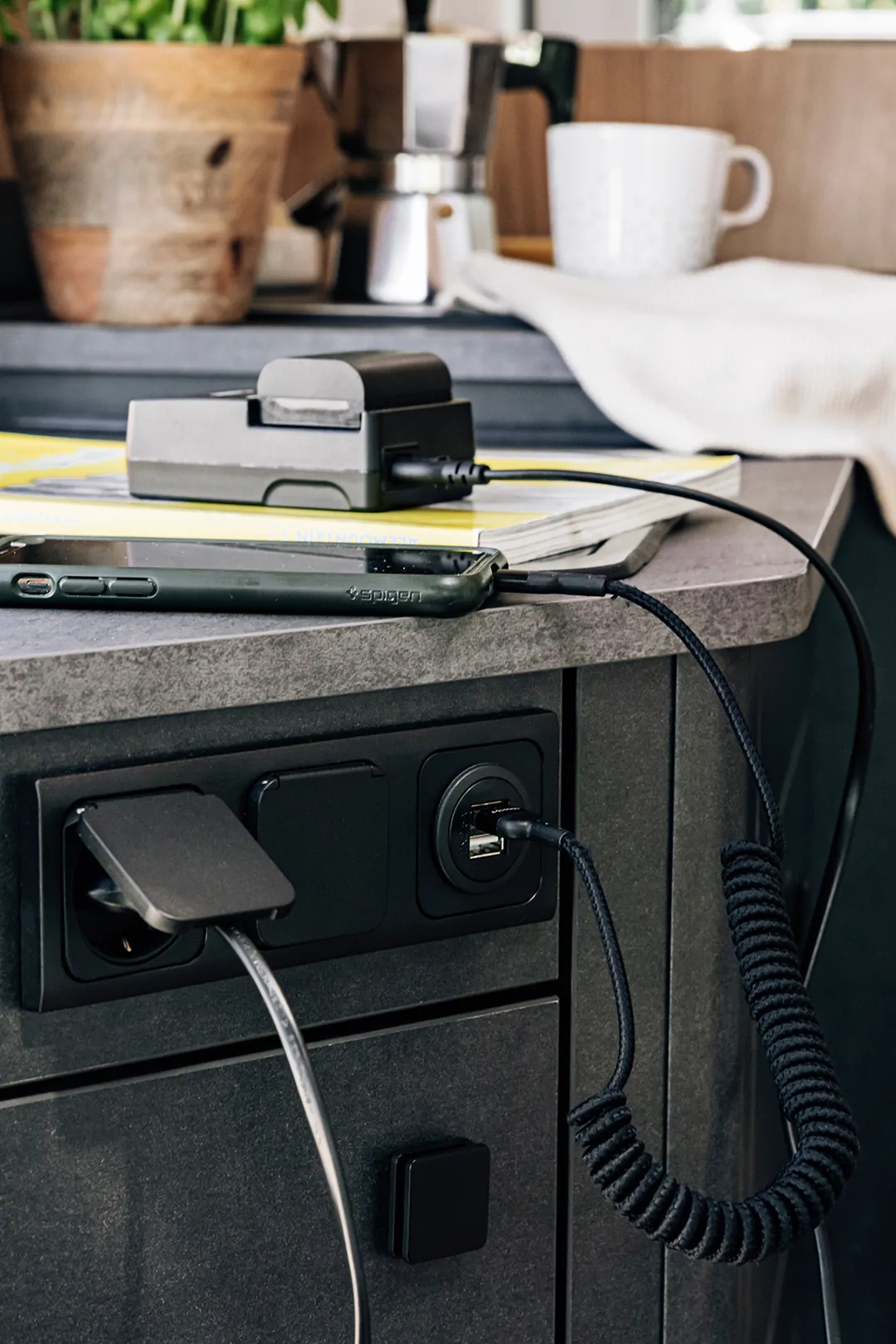 Steckdose in einem Camper mit angeschlossenen Ladegeräten und Kabeln.