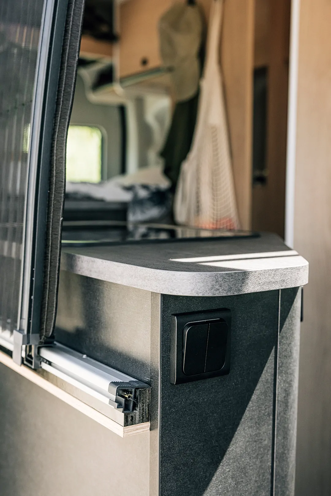 Innenansicht eines Wohnmobils mit Fokus auf einen Lichtschalter an der Küchenzeile.