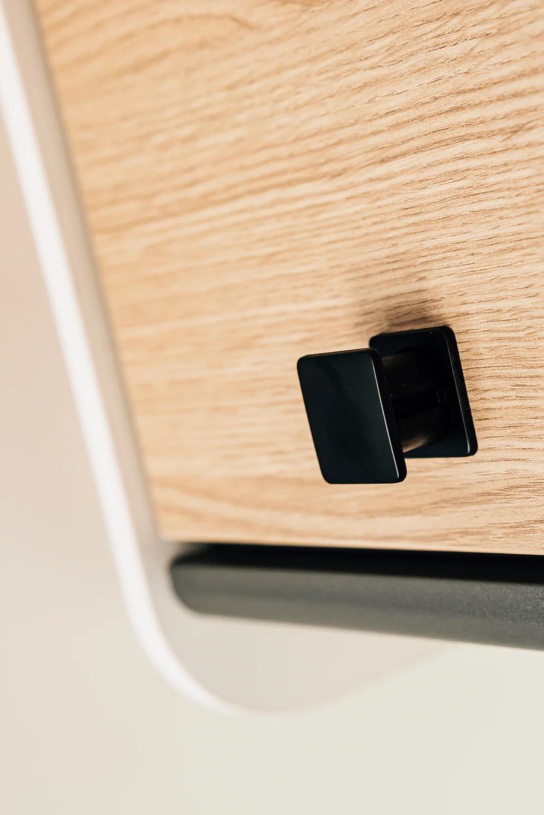 Schwarzer Push-Lock-Verschluss auf einer Holzoberfläche.
