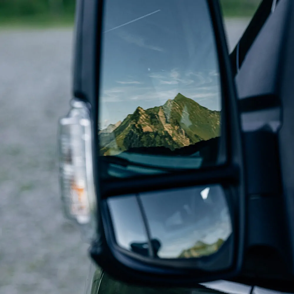 Rückspiegel eines Fahrzeugs zeigt die Reflexion eines Berges.
