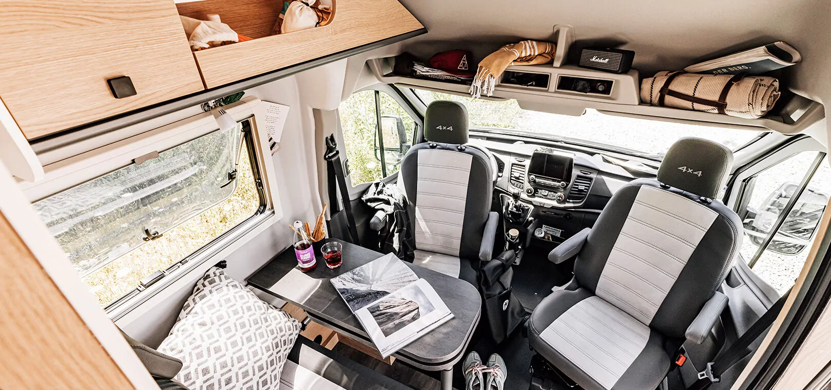 Innenraum eines Cliff 4x4 Wohnmobils mit zwei vorderen Sitzen und einem Tisch.