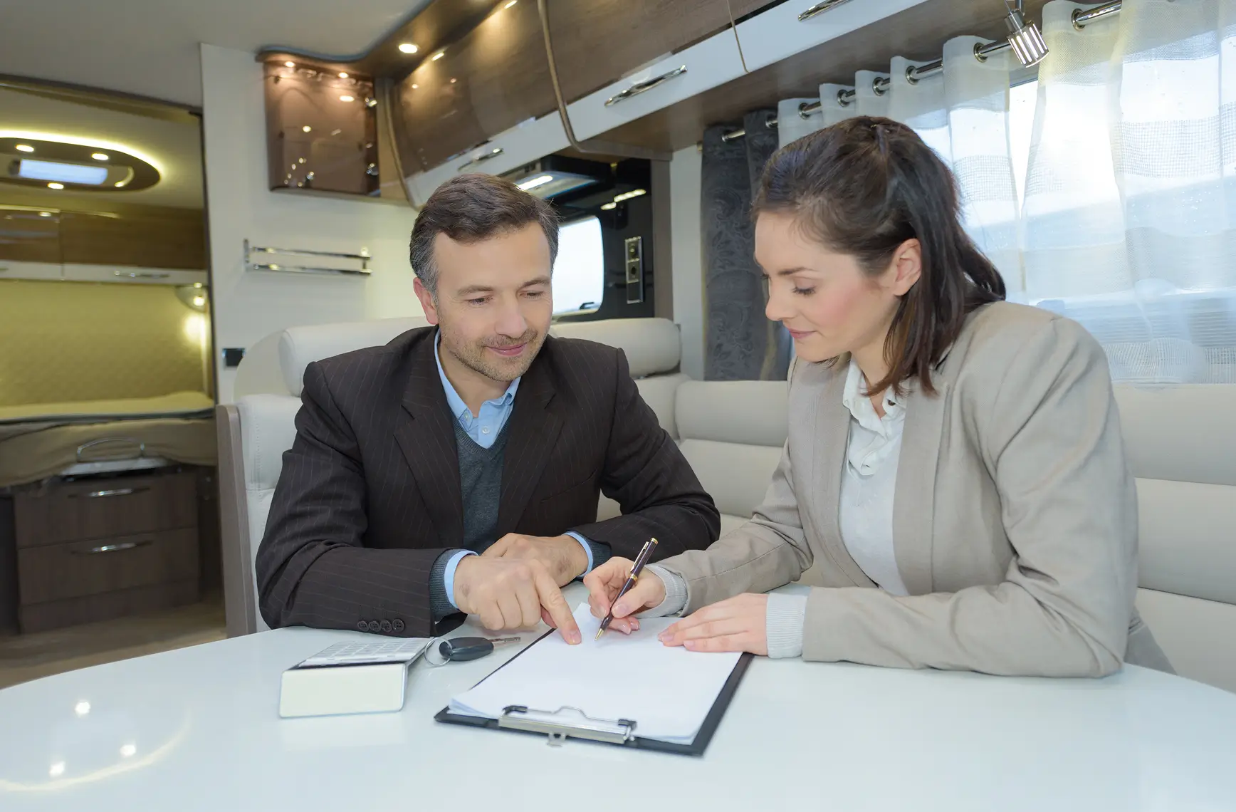 Zwei Personen unterzeichnen ein Dokument in einem Wohnmobil.