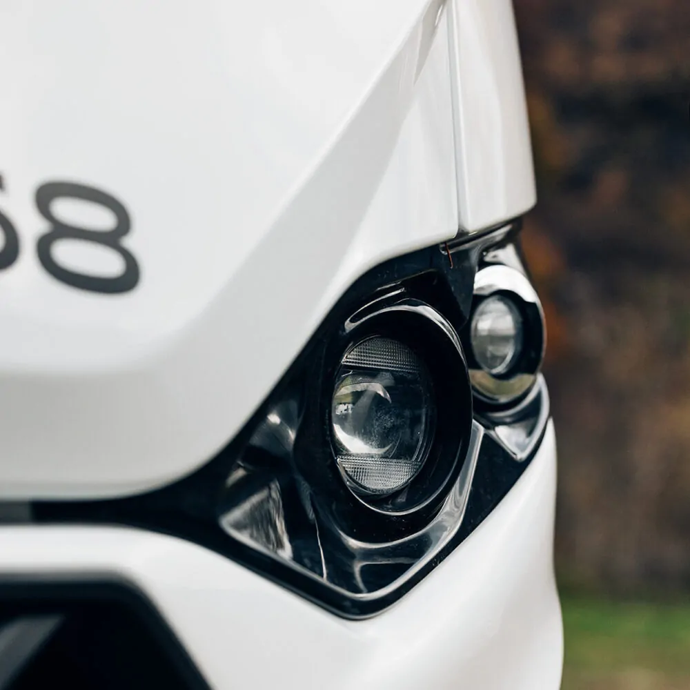 Nahaufnahme eines Scheinwerfers eines weißen Fahrzeugs.