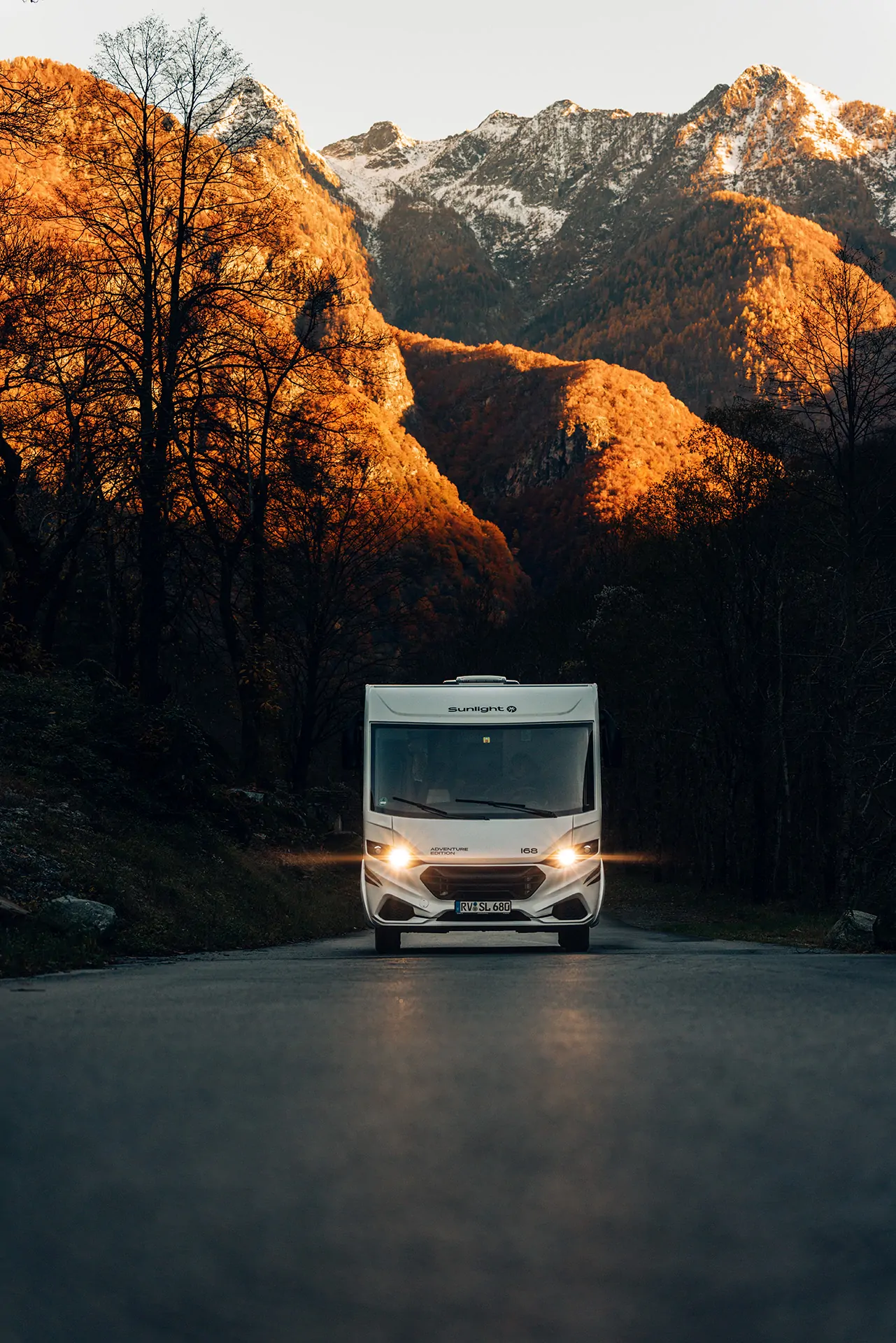 Wohnmobil Sunlight Adventure steht auf einer Straße vor herbstlichen Bergen.