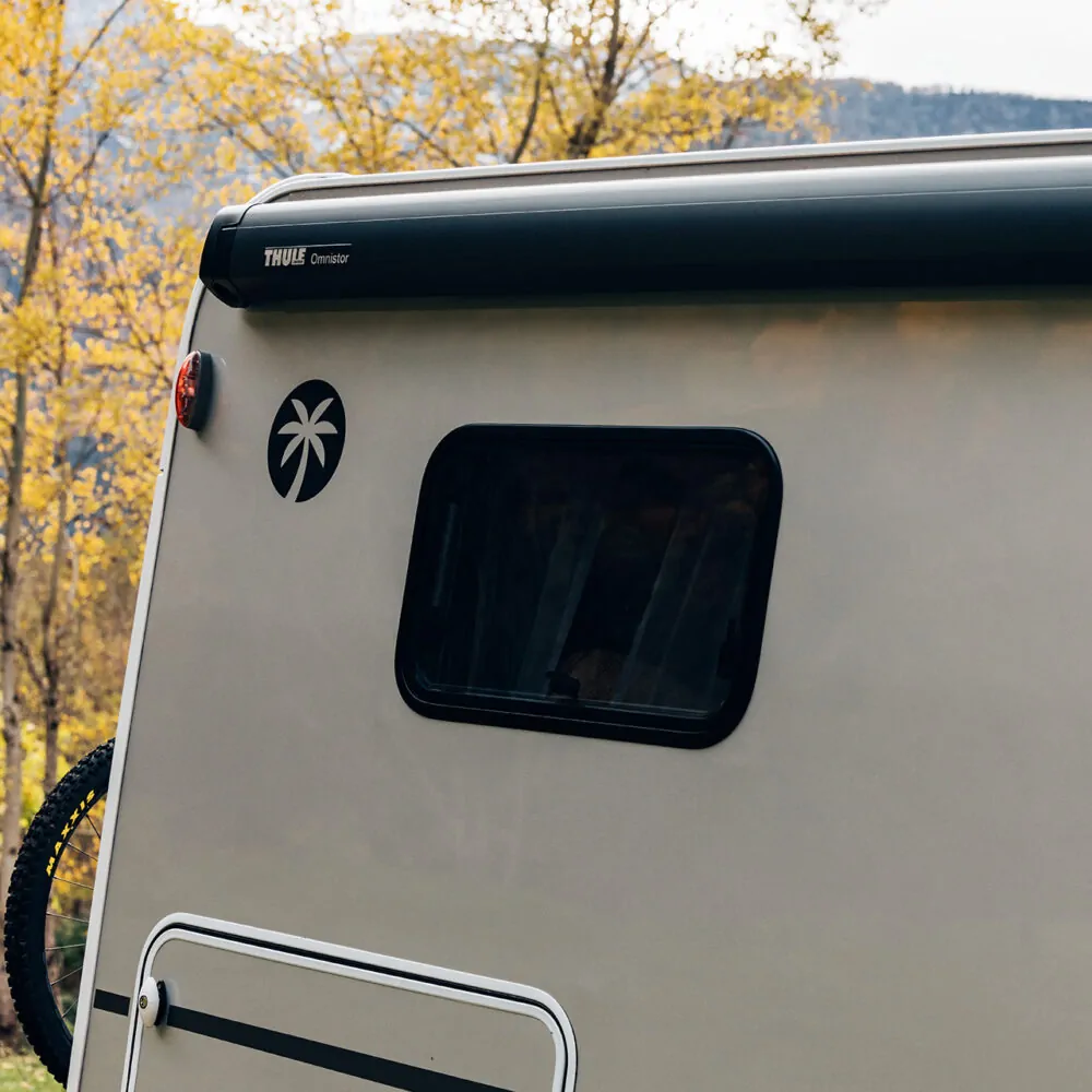Rückseite eines Wohnmobils mit einem Thule Omnistor Markisensystem und einem Palmenaufkleber.