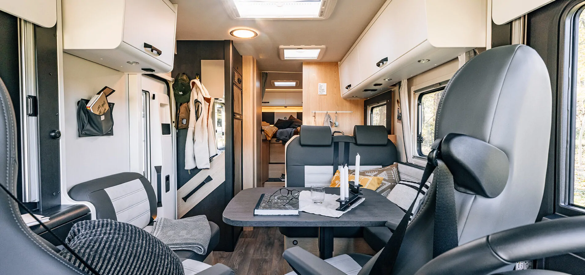 Innenansicht eines modernen Wohnmobils mit Tisch, Sitzgelegenheiten und Stauraum.
